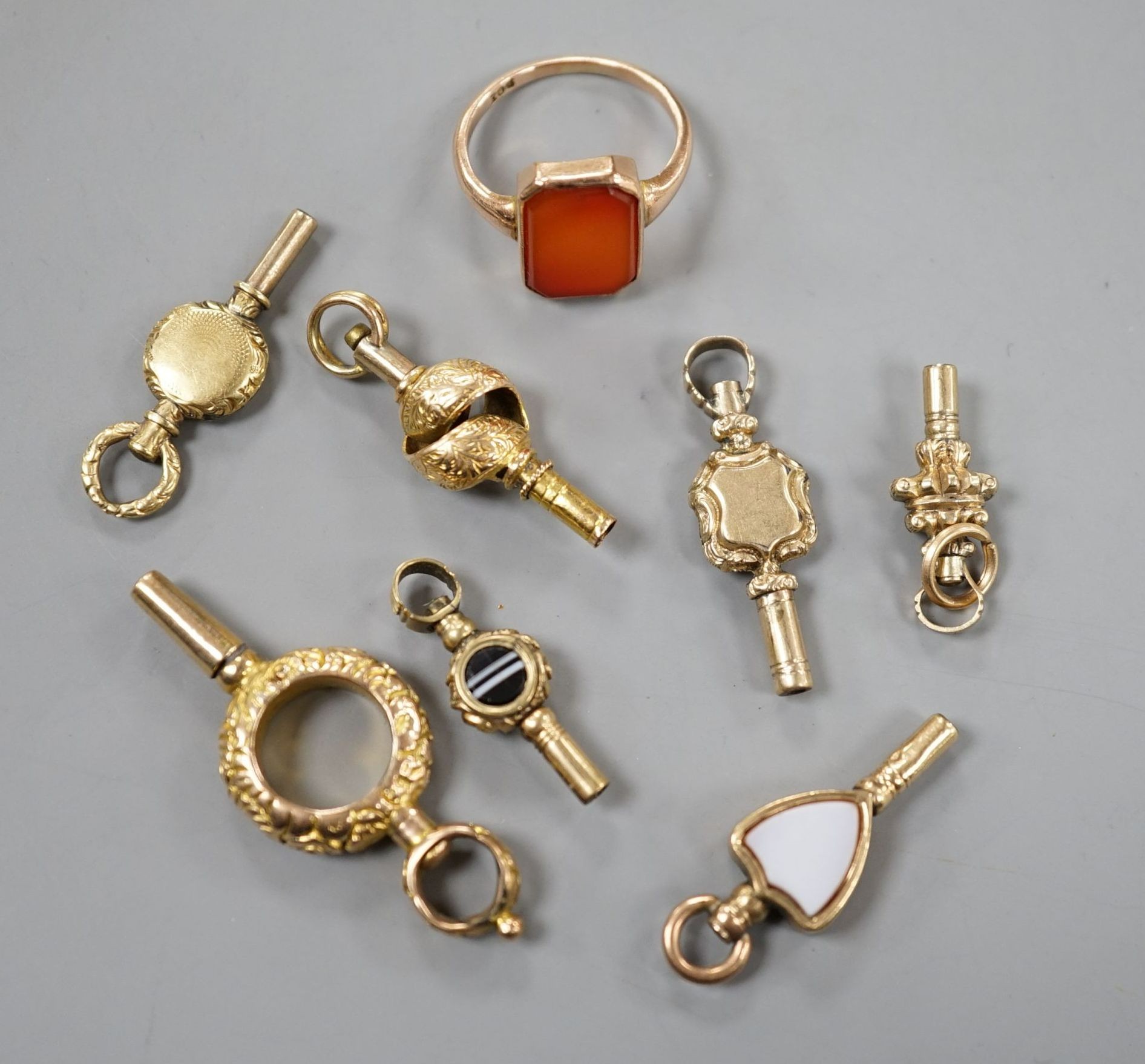 An early 20th century 9ct and carnelian set ring, size K/L, gross 2.7 grams and seven assorted watch keys including three set with chalcedony.